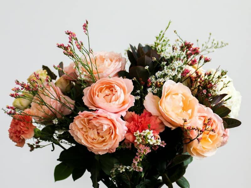 Strauß aus pfirsichfarbenen Rosen und zarten Zweigen